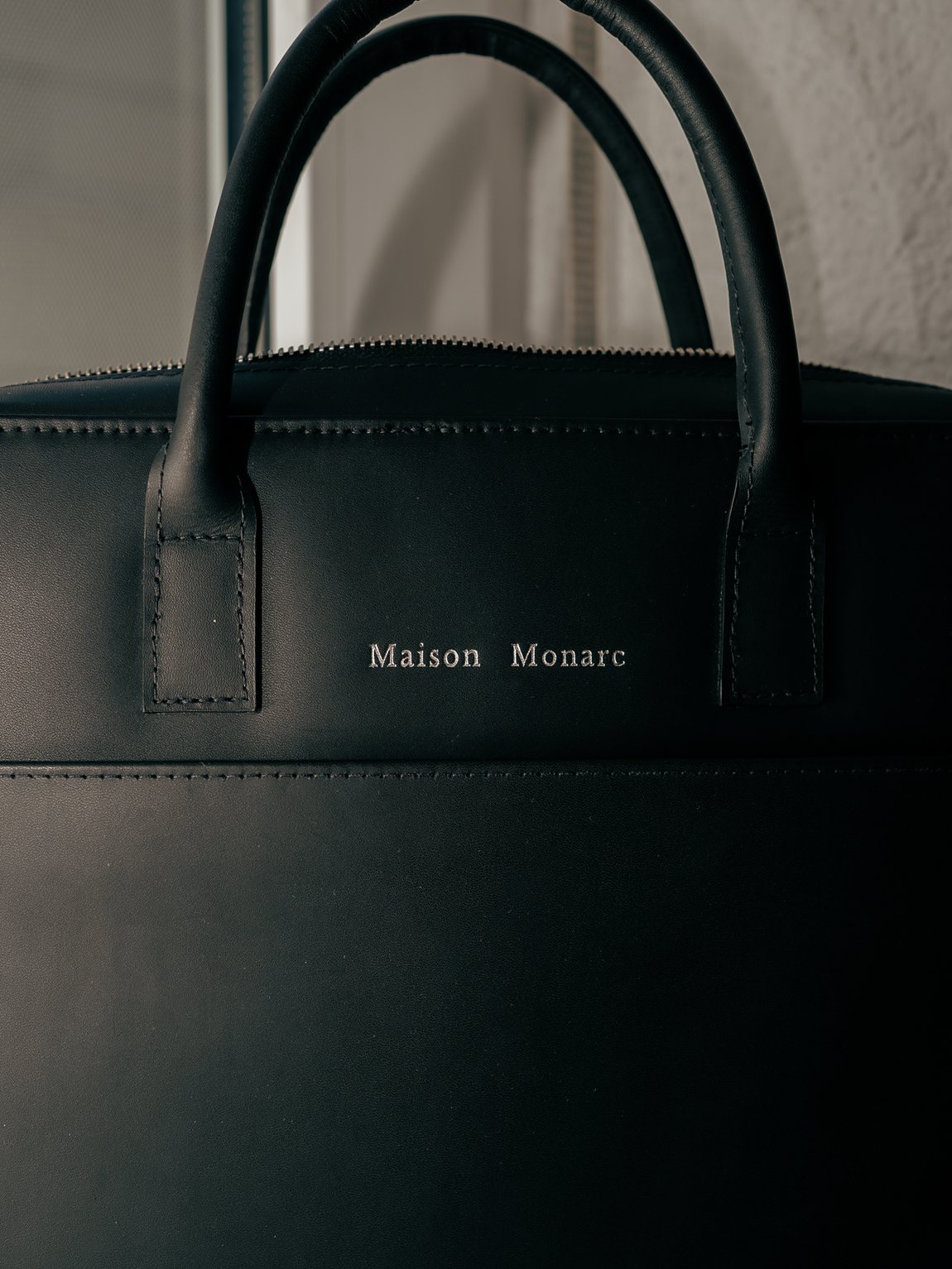 Silberne Prägung Maison Monarc auf schwarzem Leder
